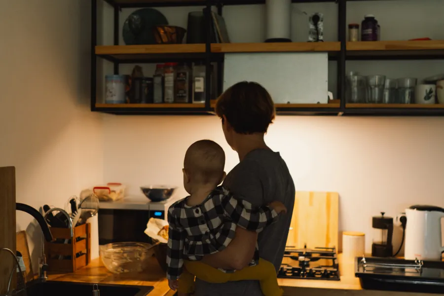 Madre con su hijo en brazos cocinando tras contratar la Tarifa de Luz y Gas Ahorro Plus de Repsol